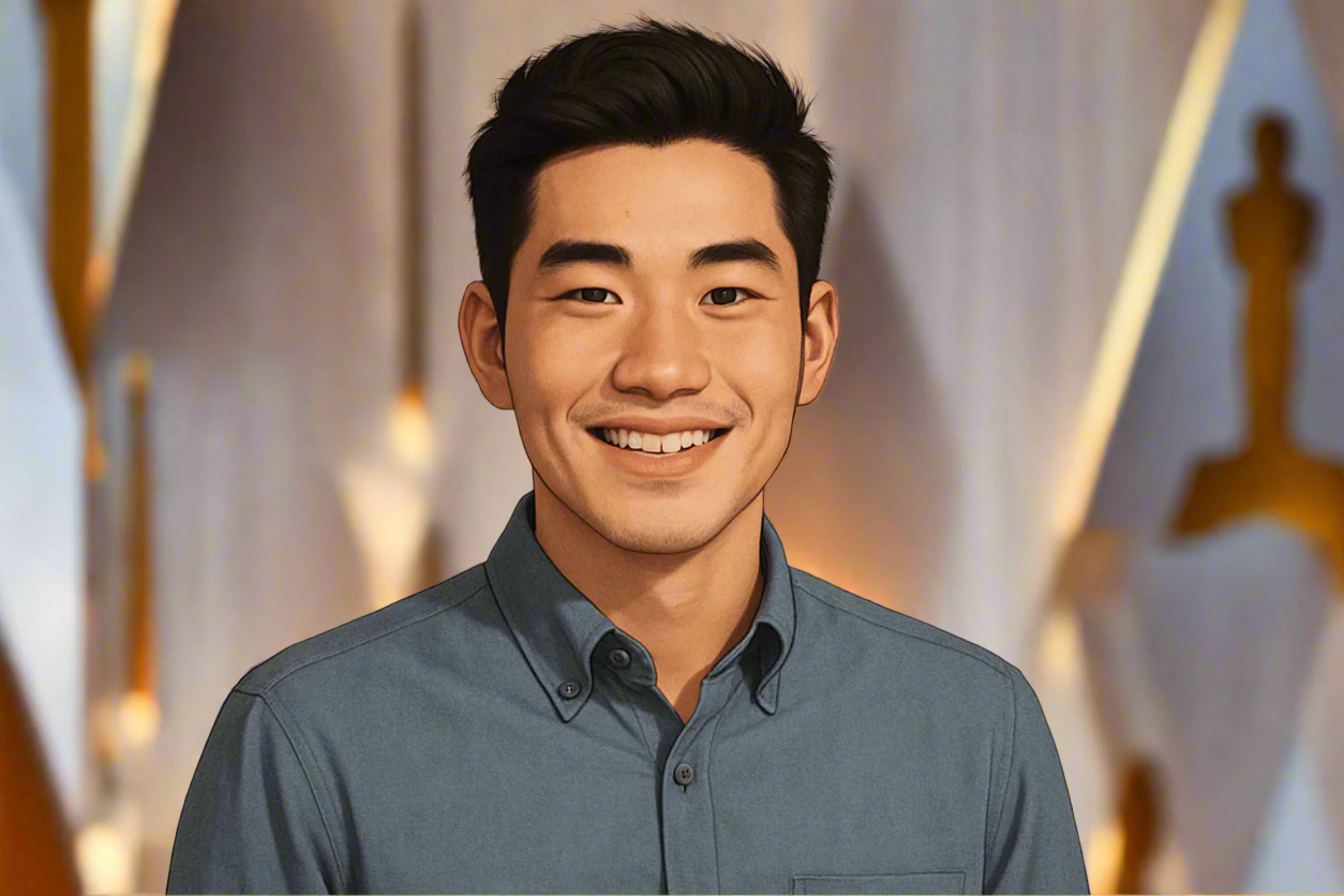 Man wearing a gray shirt with an Oscar statue in the background